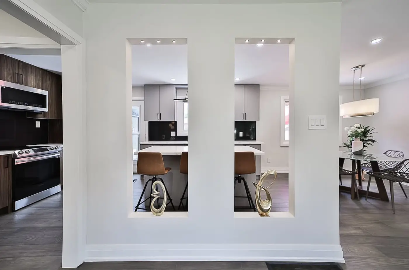 Recessed wall cutouts with decorative sculptures looking through to a contemporary kitchen island.