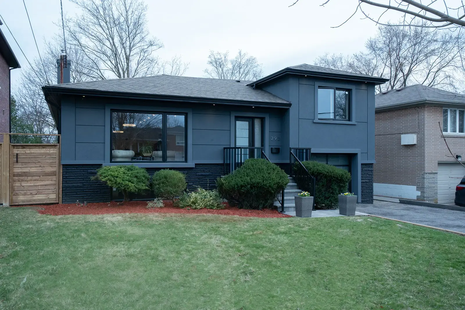 Front of the home with dark blue siding and a new lawn — 293 Betty Ann Drive, North York