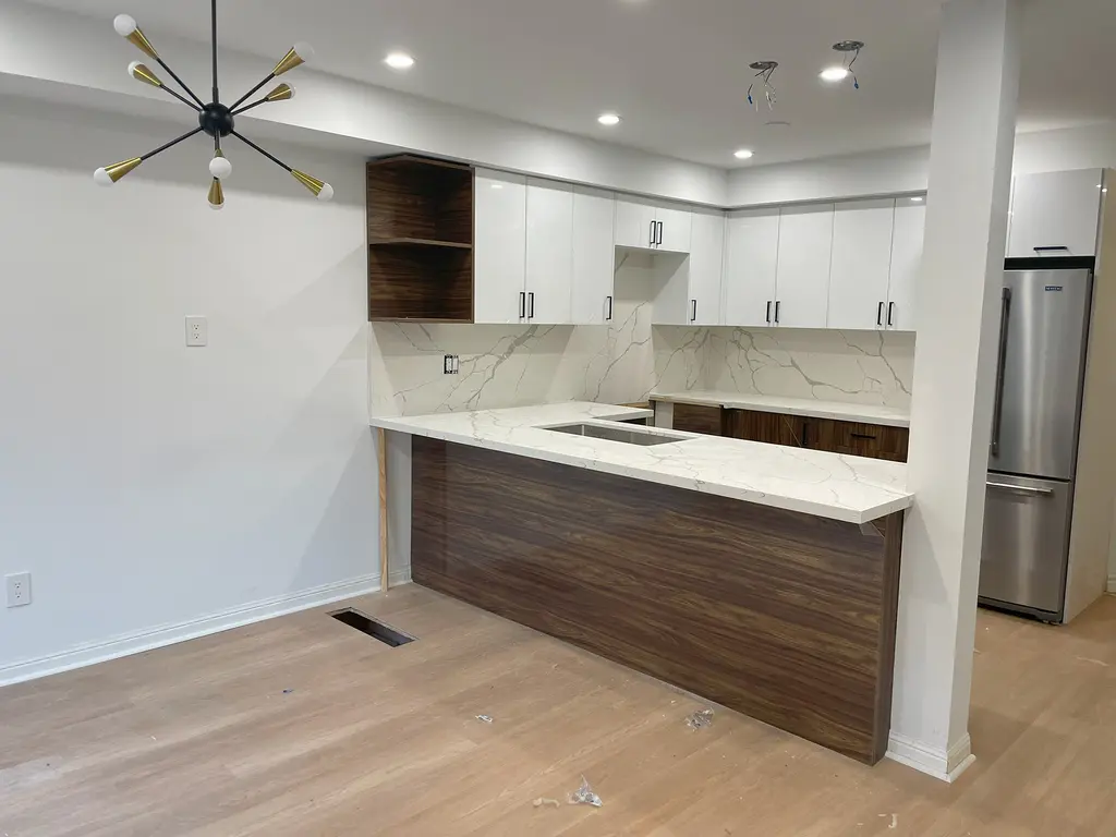 Renovated townhouse kitchen with a wood-grain peninsula and white cabinets — 556 Bondi Ave, Newmarket