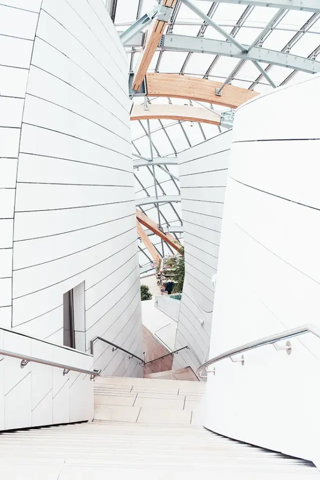 Curved modern staircase with white paneled walls beneath a glass and timber atrium ceiling