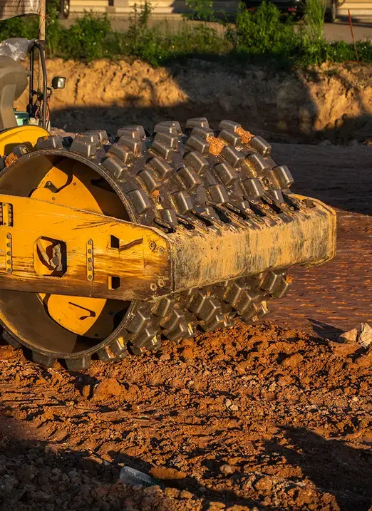 Padfoot roller compactor drum compacting soil on a civil construction earthworks site